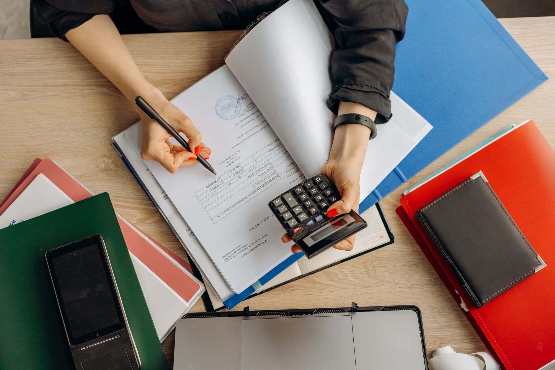 An accountant analysing financial documents with a calculator at a desk