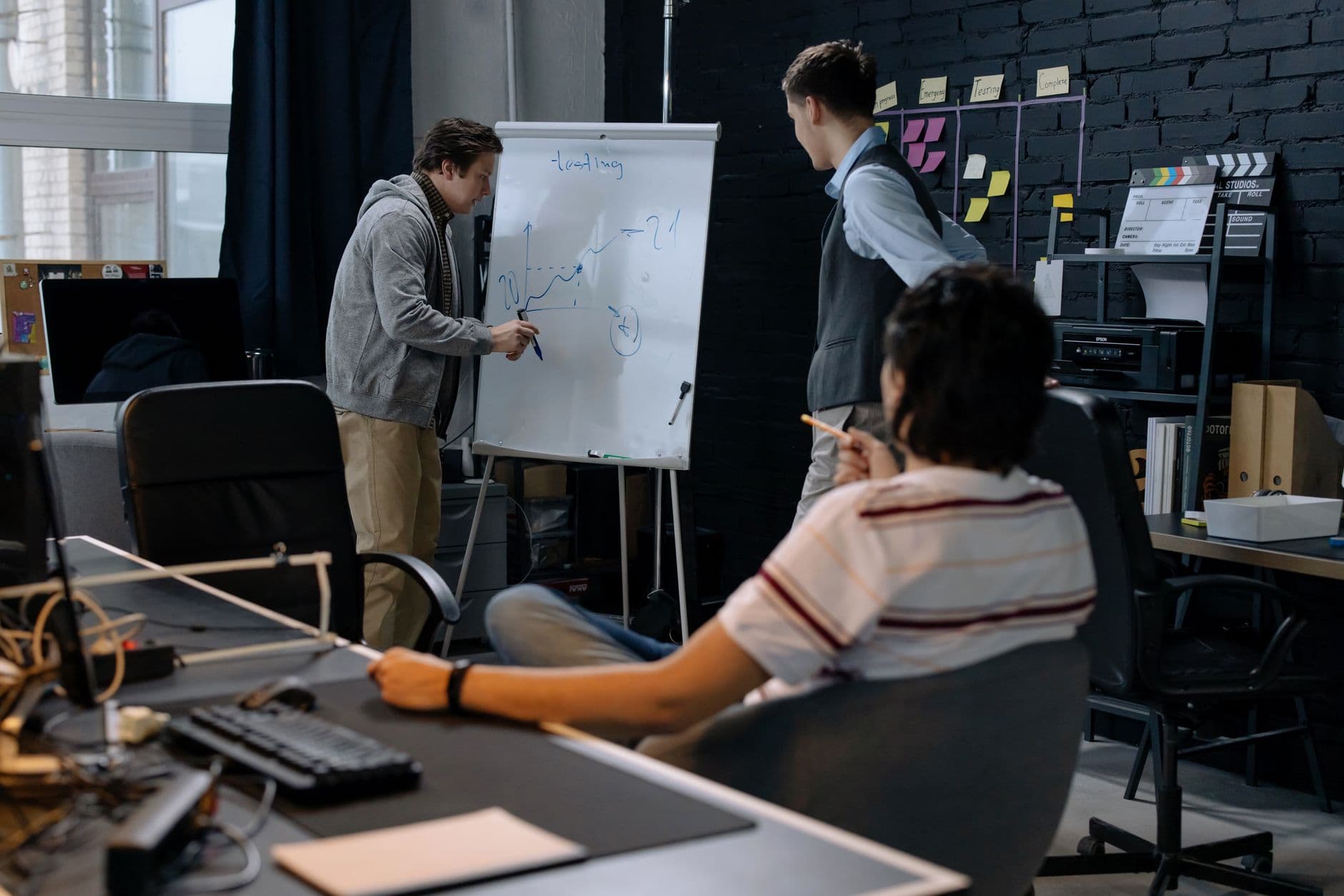 A small operations team reviewing a workflow board with sticky notes and a laptop in a bright startup office