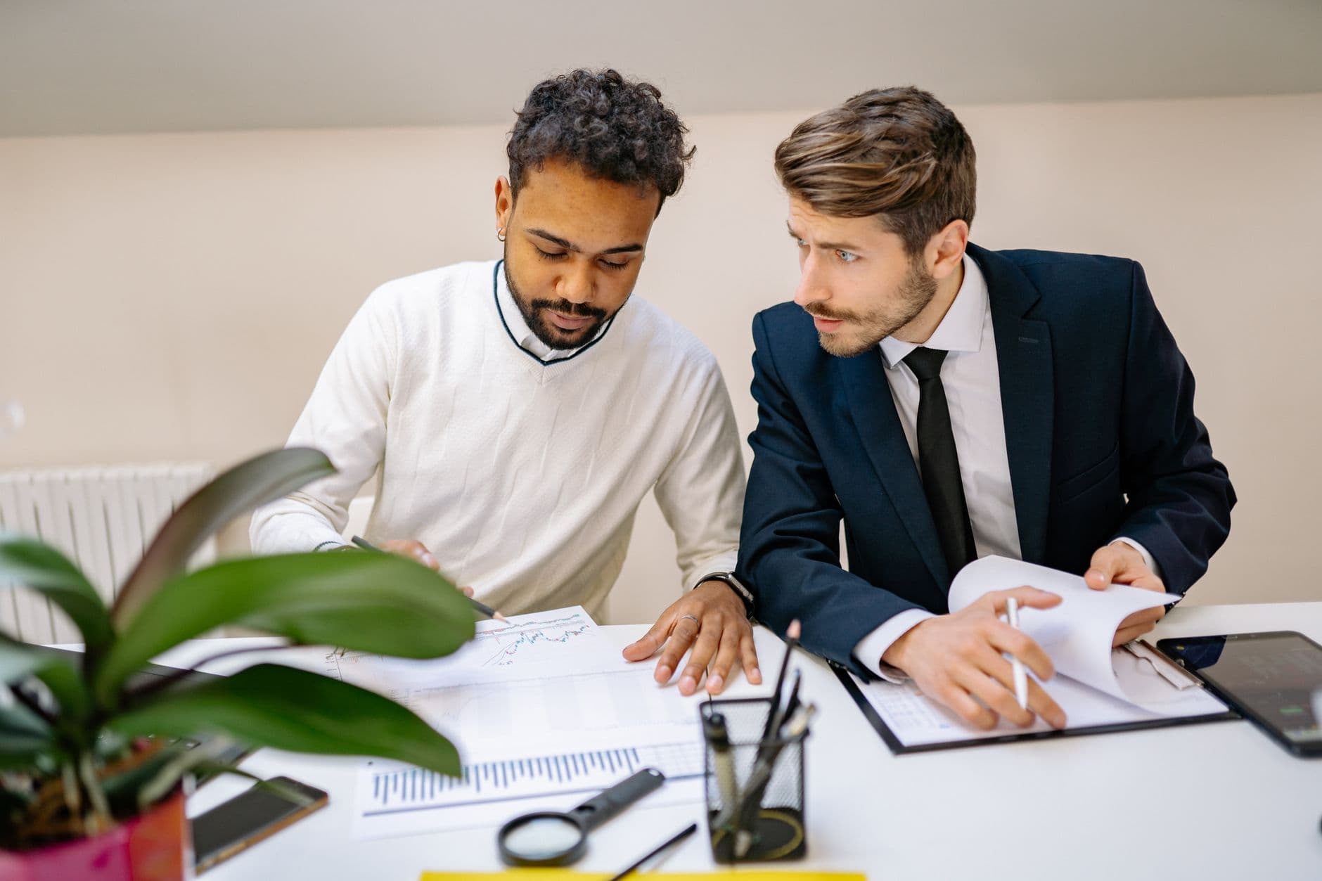 Two colleagues at a desk reviewing an operations dashboard and a printed plan together