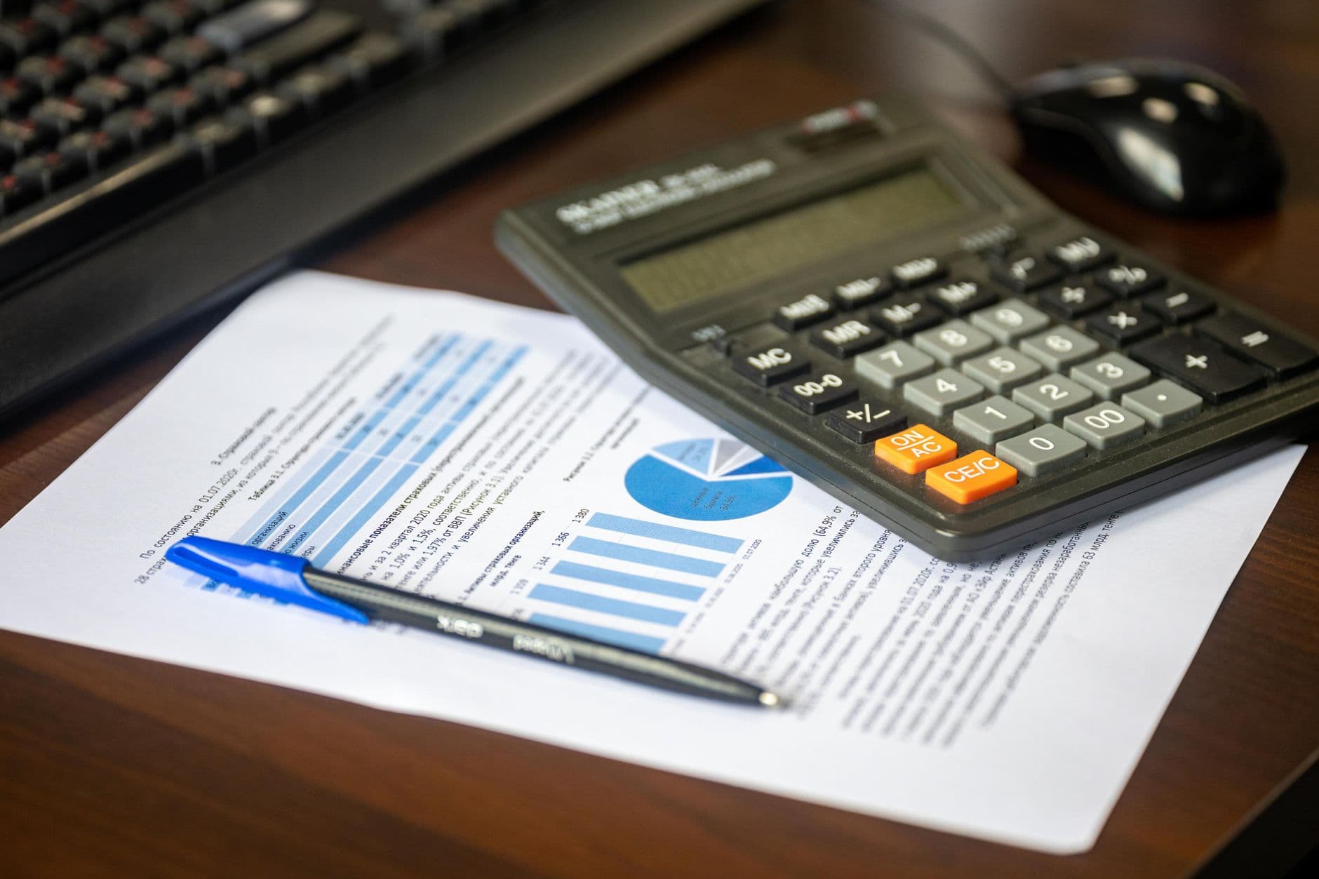 Desk with a calculator, financial report and pen, representing the cost of hiring a fractional CTO