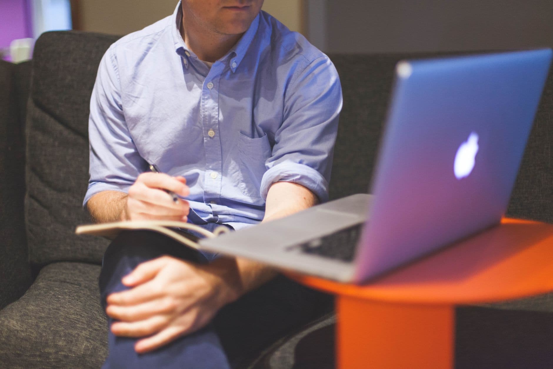 A founder working remotely with a laptop and notebook, taking notes