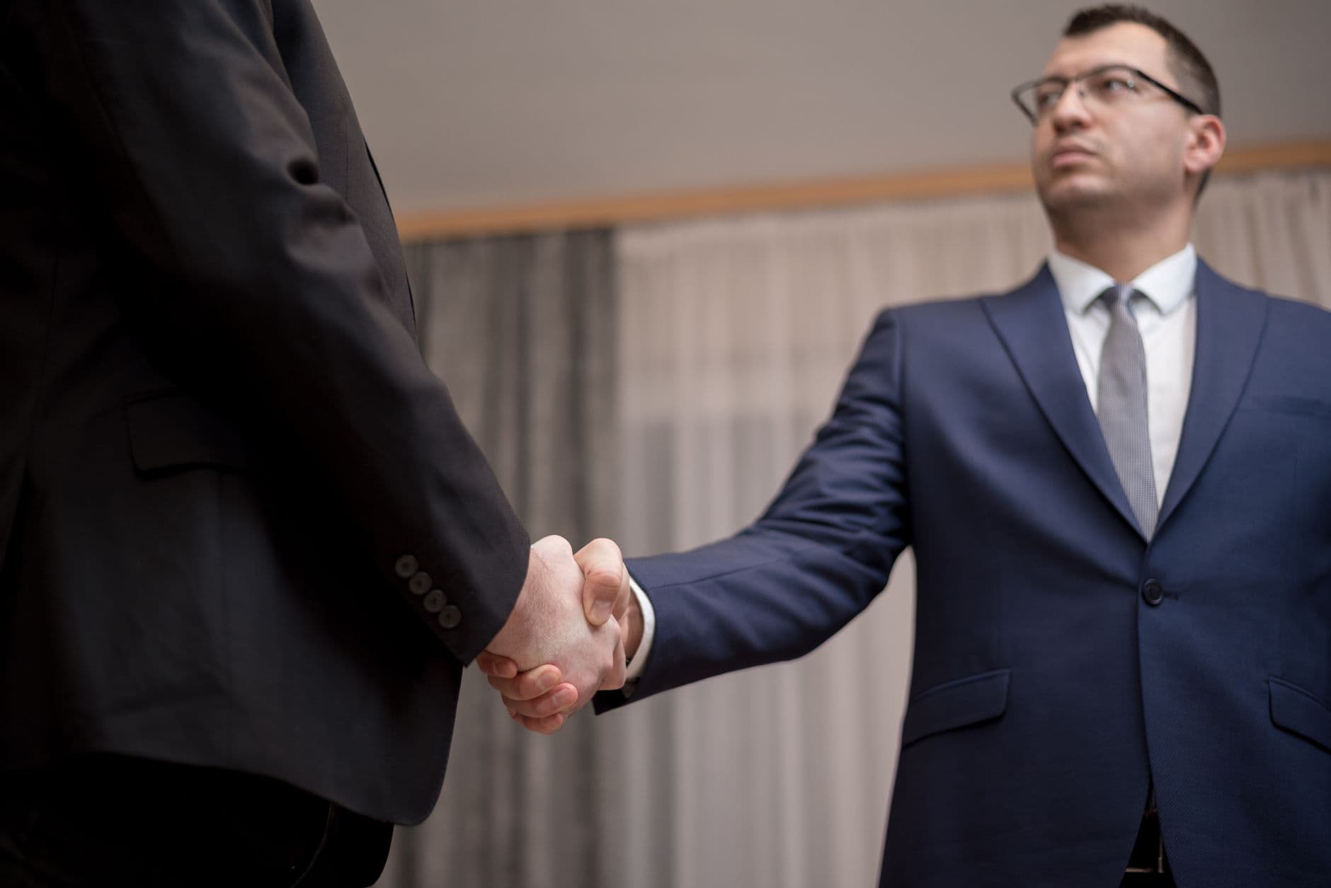 A founder and a fractional COO shaking hands across a desk in a bright modern office
