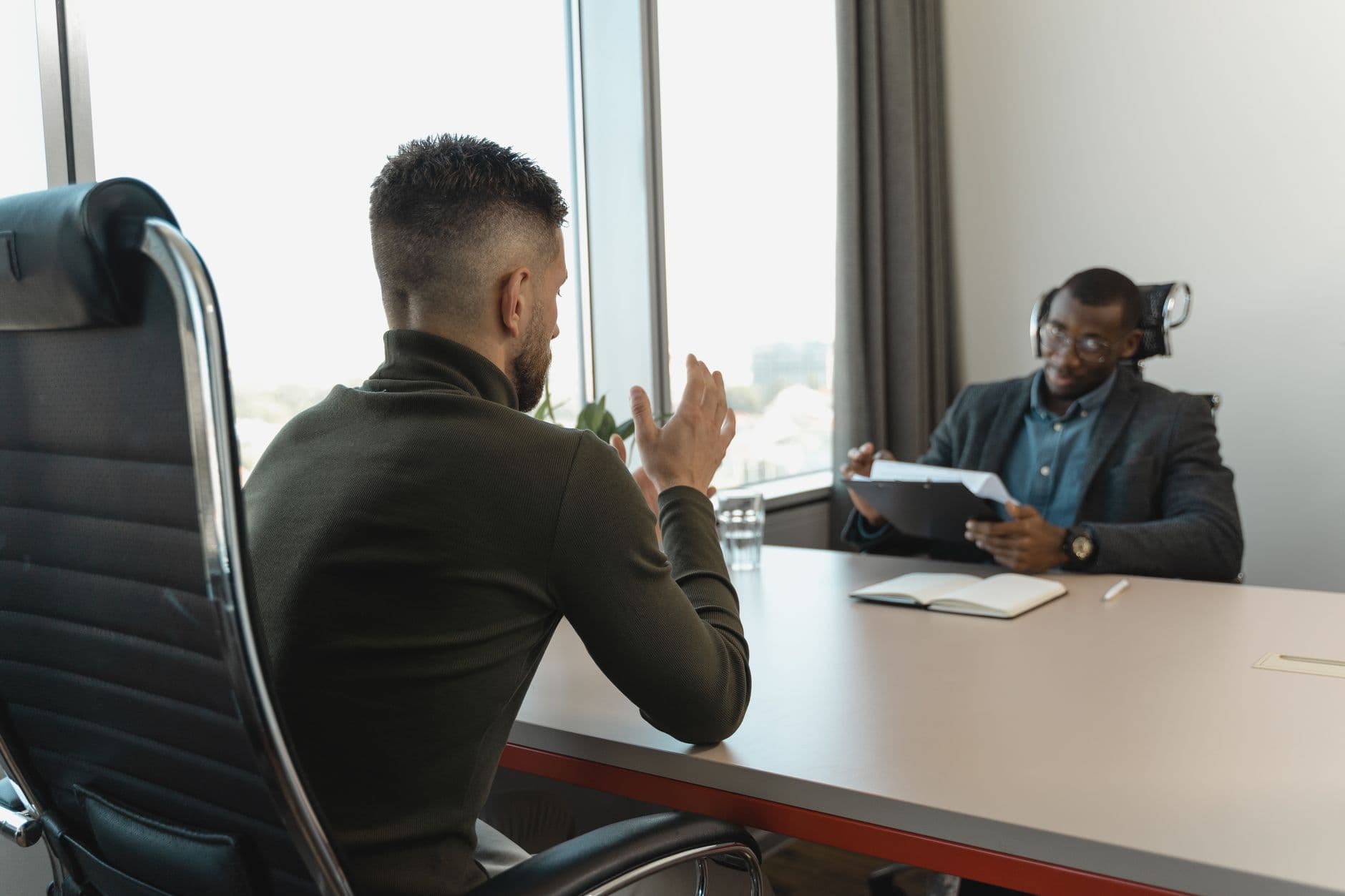 Two professionals in a focused interview conversation across a meeting table